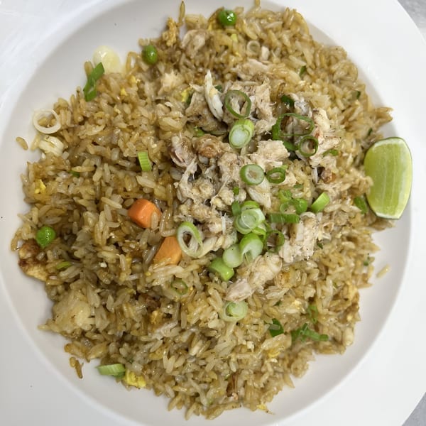 Crab fried rice with peas, carrots, and green onions, garnished with a lime wedge.