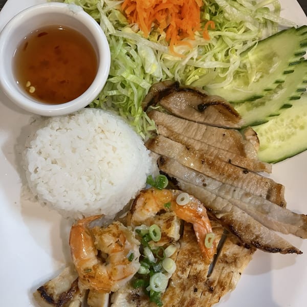 Vietnamese grilled pork and shrimp with rice, shredded lettuce, carrots, cucumber, and dipping sauce.